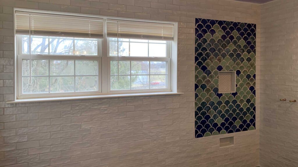 Bathroom wall and shower tiled with two niches.