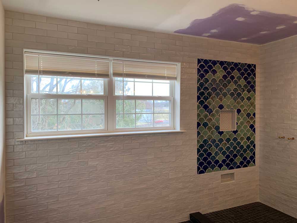 Tiled bathrooms wall and shower area with two tiled niches.
