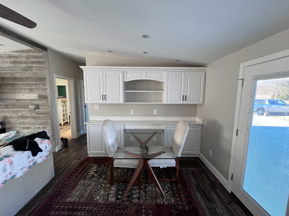 Office buildout with white cabinets, crown molding, glass table, and quartz countertops.