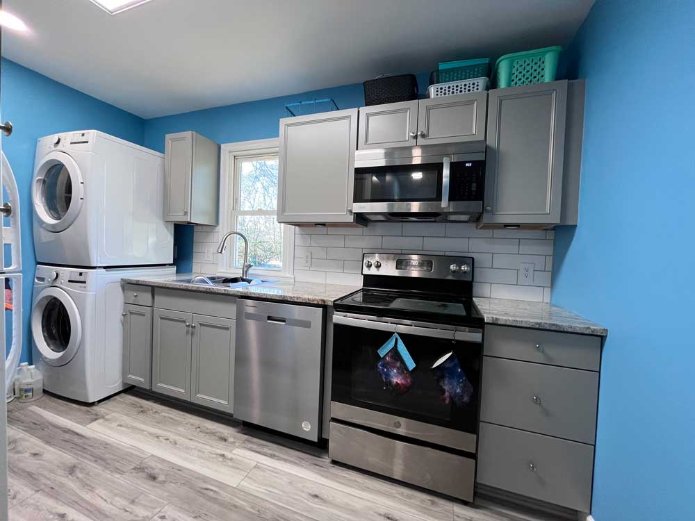 Kitchen with grey cabinets with tiled backsplash.