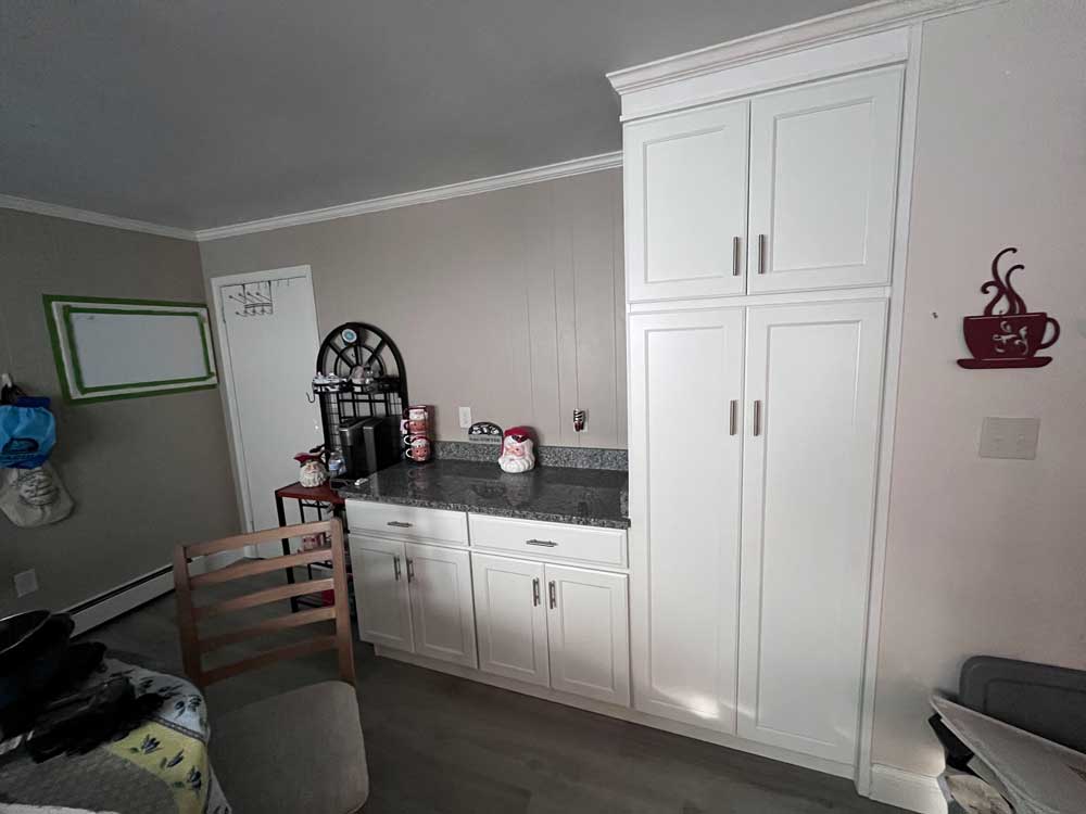 Coffee bar area with white cabinets, crown molding, granite countertops, and LVP flooring